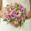 In the heart of Sands End, a bridal bouquet dances with romantic joy, gently clasped against the lace veil of a bride's wedding gown. The arrangement is a visual melody: tender lilac and blush-pink roses unfurl with youthful energy, their petals resonating with the softest hint of fragrance, while sprightly green button chrysanthemums add a vibrant, contemporary twist and a lively textural play, reminiscent of the area's riverside vitality. Pink alstroemeria lilies blush beneath the golden sunlight, their petals streaked with dark pink and yellow, teasing out a delicate exoticism that echoes the diversity of local gardens. Ethereal sprays of baby's breath float through the bouquet, their small snowy blooms suspended like wisps of morning fog over Eel Brook Common. Deep green leaves offer a lush framework, elevating the gentle hues while anchoring the design in nature. This bouquet seems to capture the spirit of a sunny day in Sands End, radiating the promise of new beginnings and heartfelt celebration. Every bloom and leaf is expertly placed, creating a tranquil yet joyful mood-the perfect floral companion for a local bride or as inspiration for those dreaming of a beautiful, meaningful wedding by the Thames.